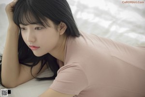 A woman laying on top of a white bed.