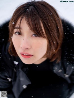 A woman in a black coat is walking in the snow.