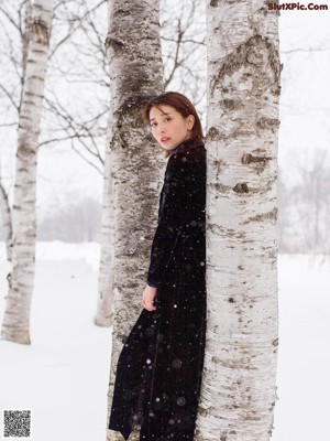A woman in a black coat standing in the snow.