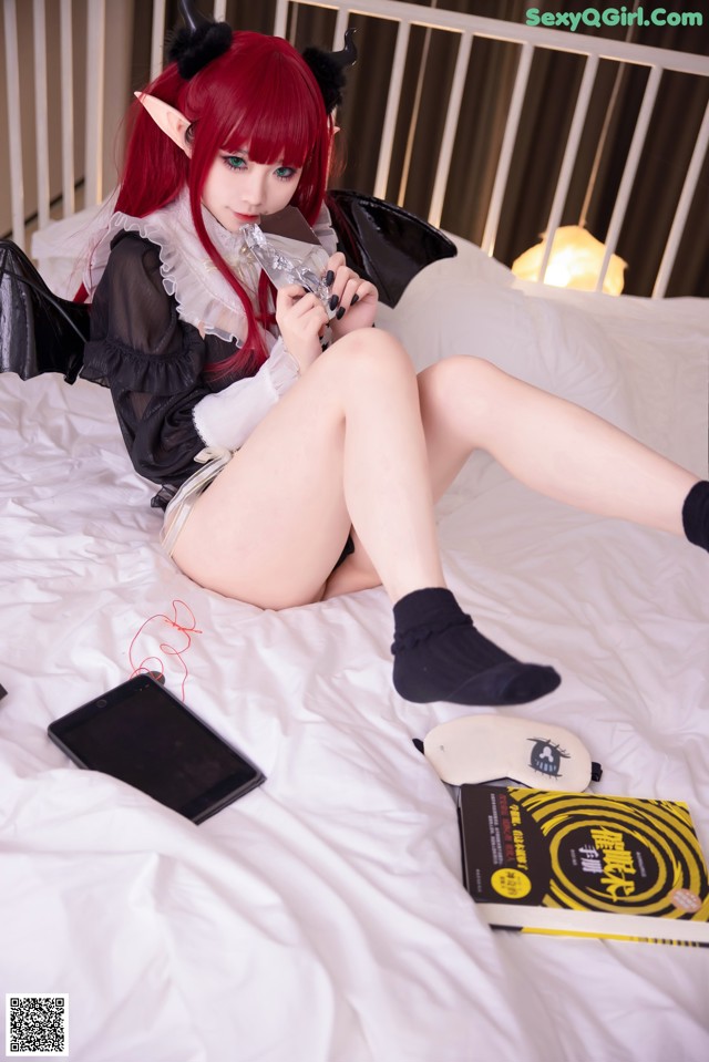 A woman sitting on a bed holding a cell phone.