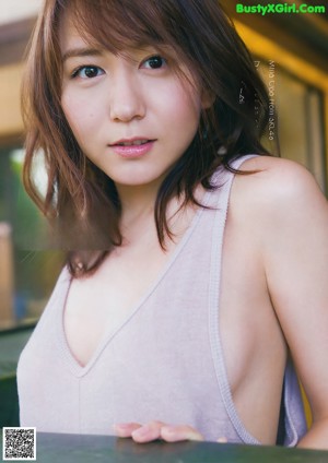 A woman in a gray shirt is posing for a picture.