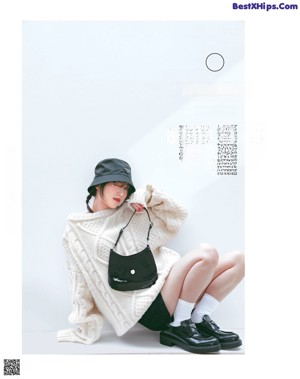 A woman sitting on the ground next to a bag.