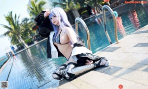A woman with blue hair sitting on the edge of a pool.