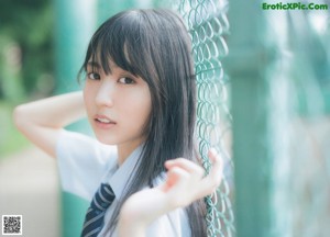 A young woman in a school uniform standing by a window.