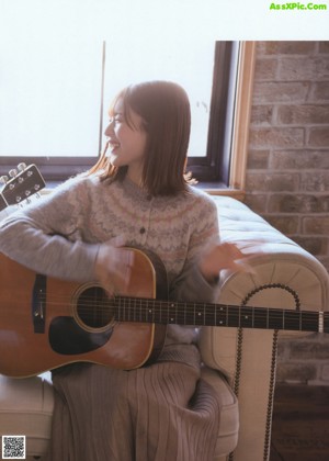 A woman standing by a window looking out the window.